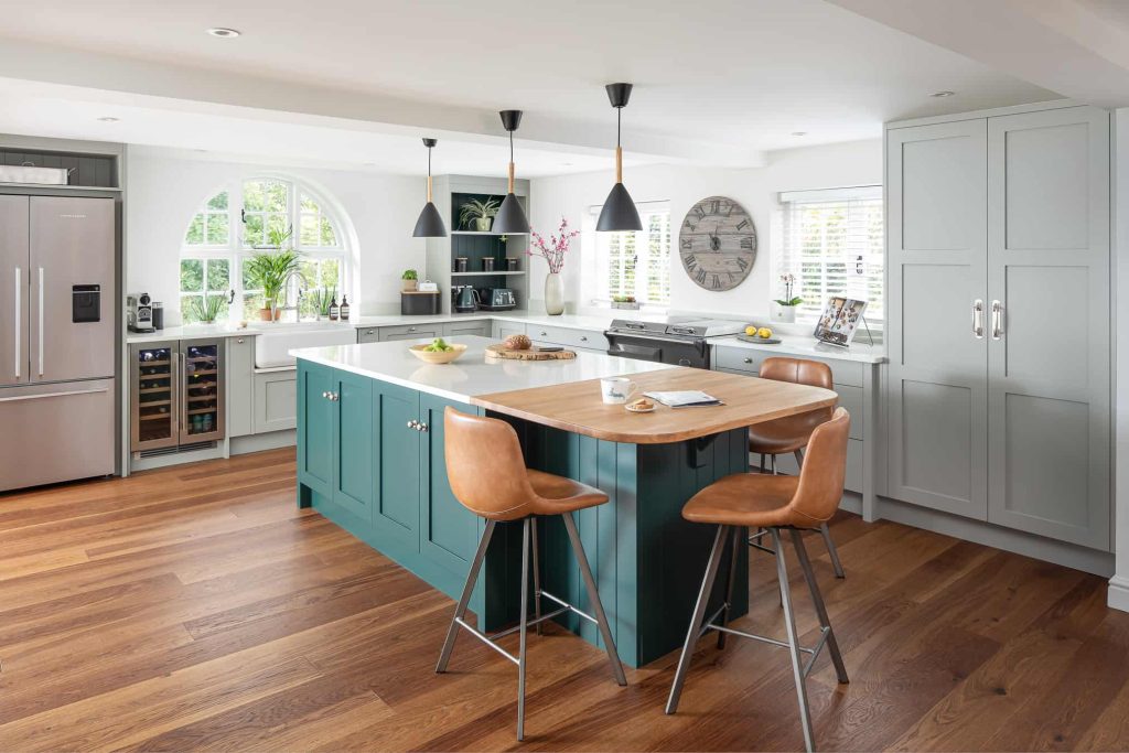 John Lewis of Hungerford luxury shaker style country kitchen with wooden flooring and grey cabinetry with a green kitchen island and wooden stools