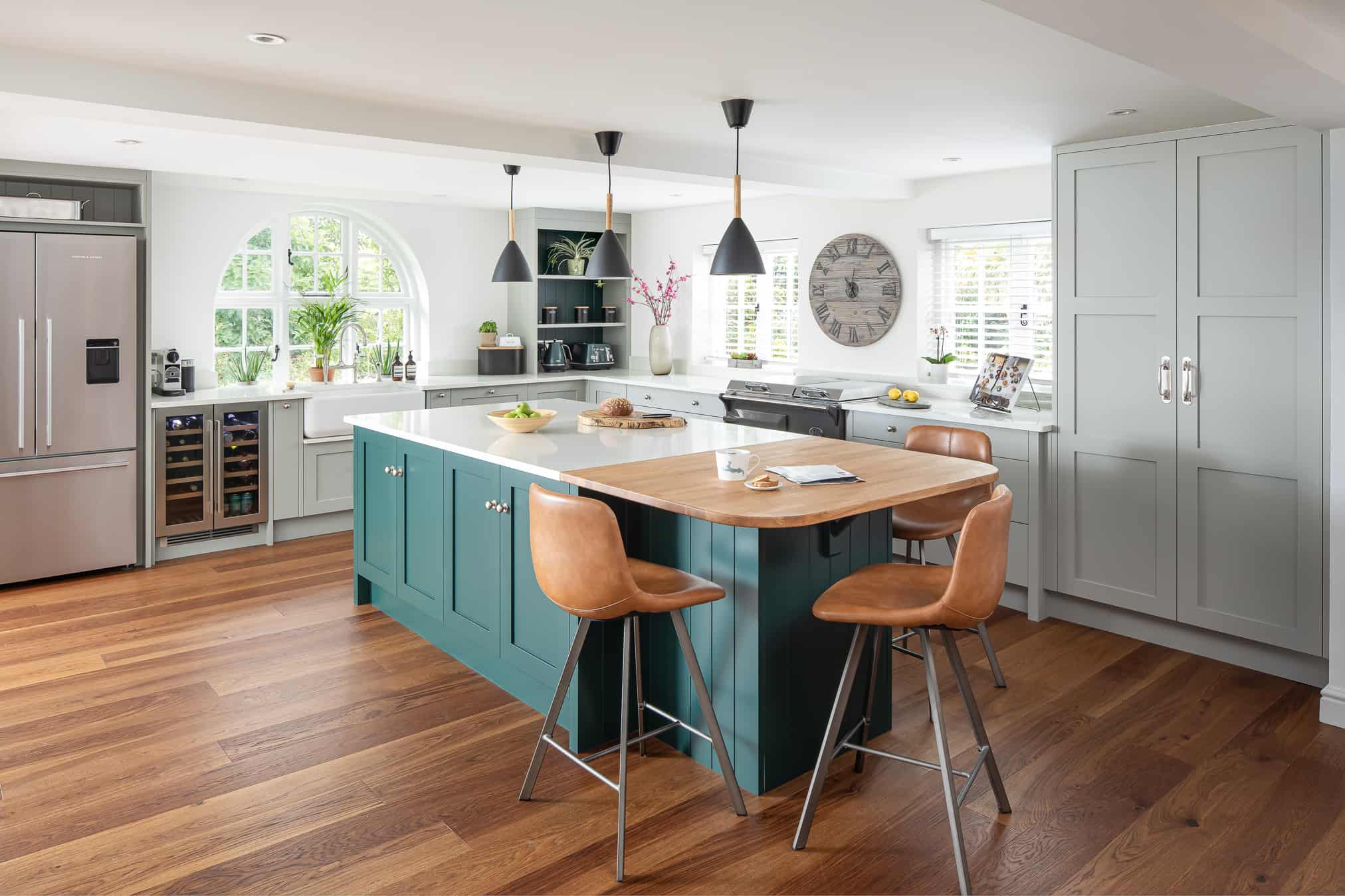John Lewis of Hungerford luxury shaker style cottage kitchen with wooden flooring and grey cabinetry with a green kitchen island and wooden stools