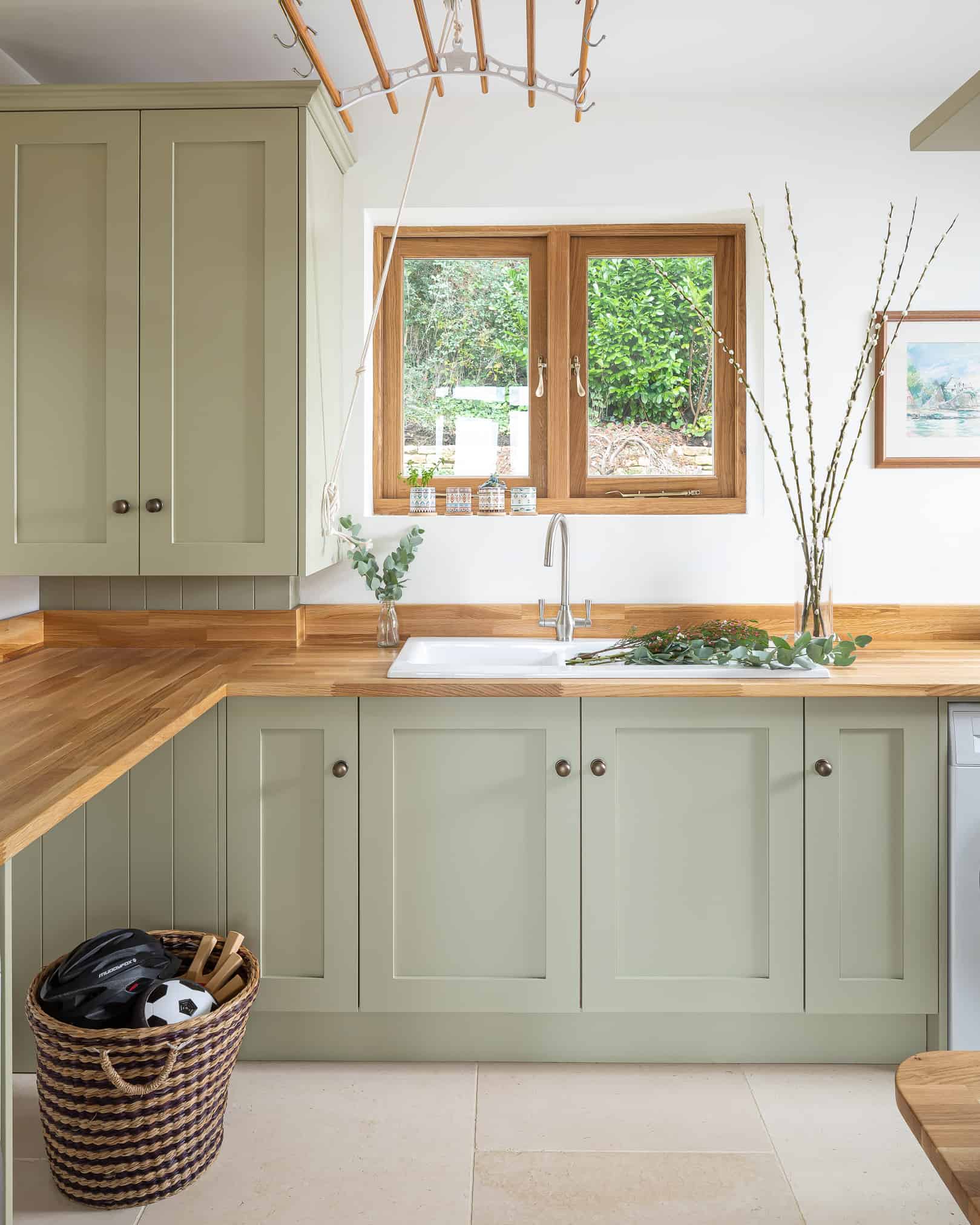 John Lewis of Hungerford luxury shaker kitchen in pale green cabinetry with wood worktops and kitchen window above a white sink