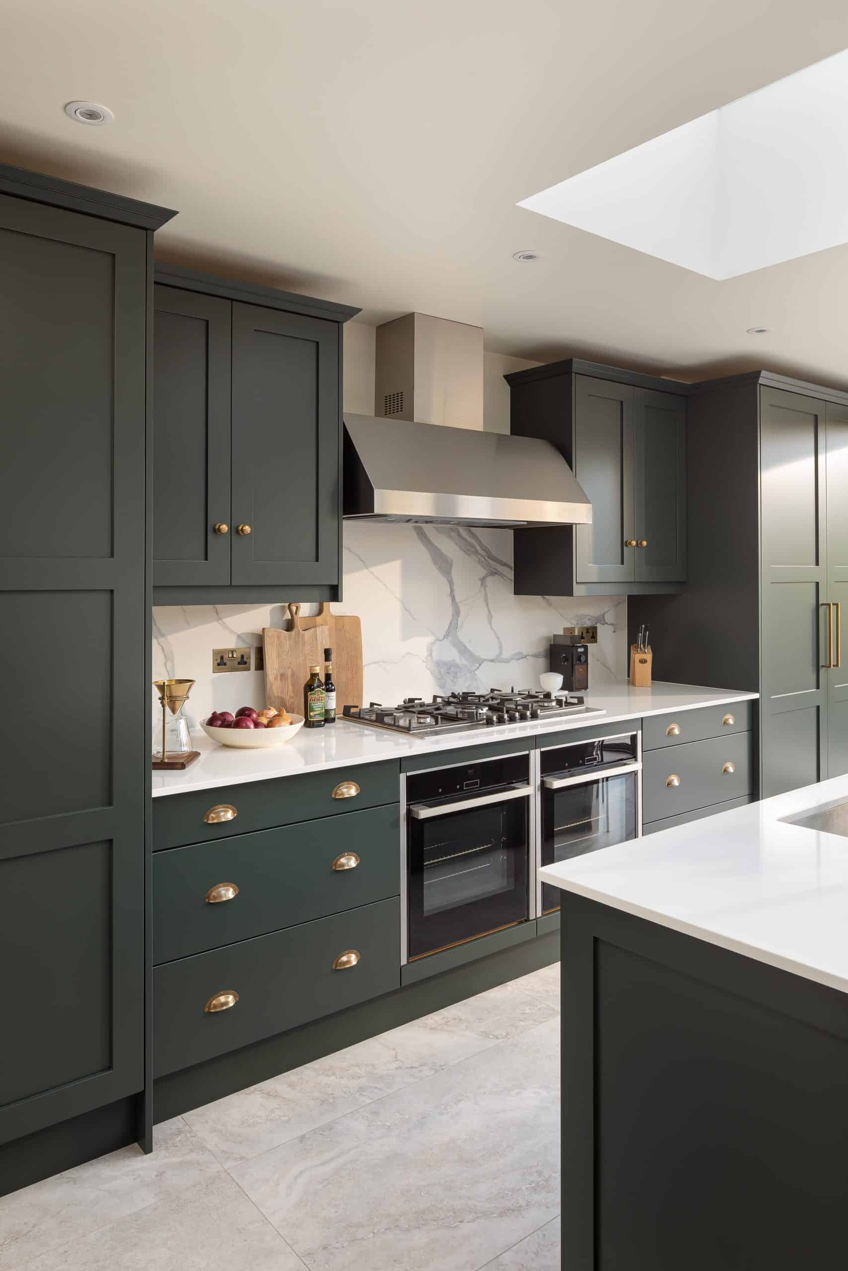 John Lewis of Hungerford luxury shaker kitchen in deep green with marble splashback and white worktops and kitchen island with brass metal cabinetry handles
