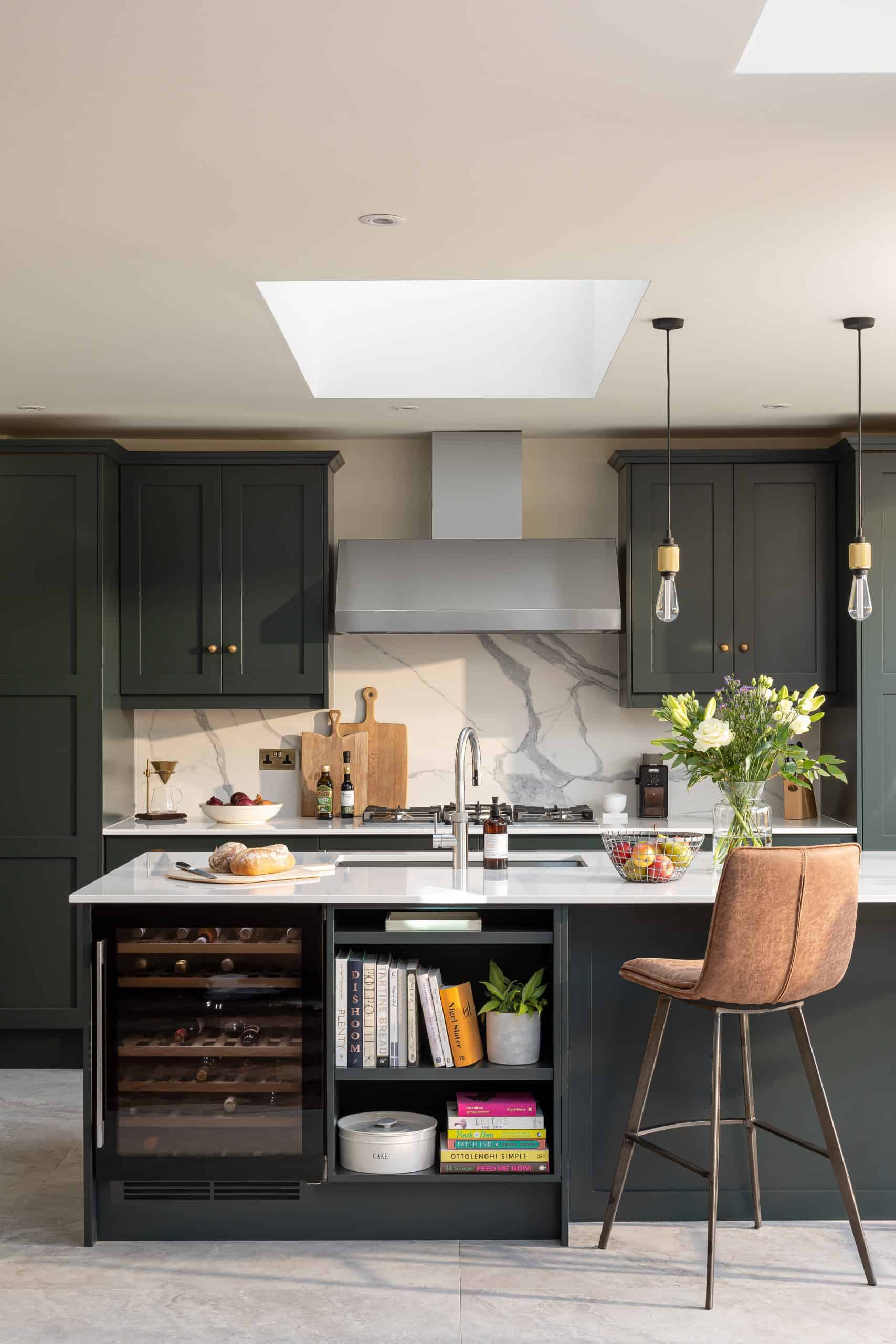 John Lewis of Hungerford luxury kitchen with kitchen island and stone flooring with a marble splashback in dark green cabinetry